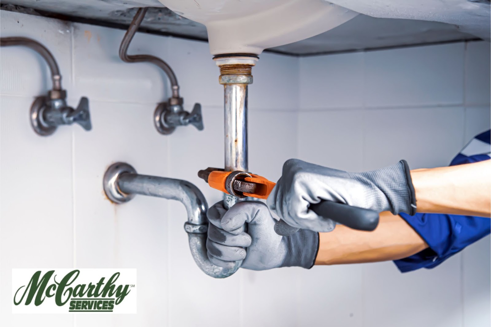 McCarthy Plumber fixing under sink piping with pipe wrench in Arlington, VA, home