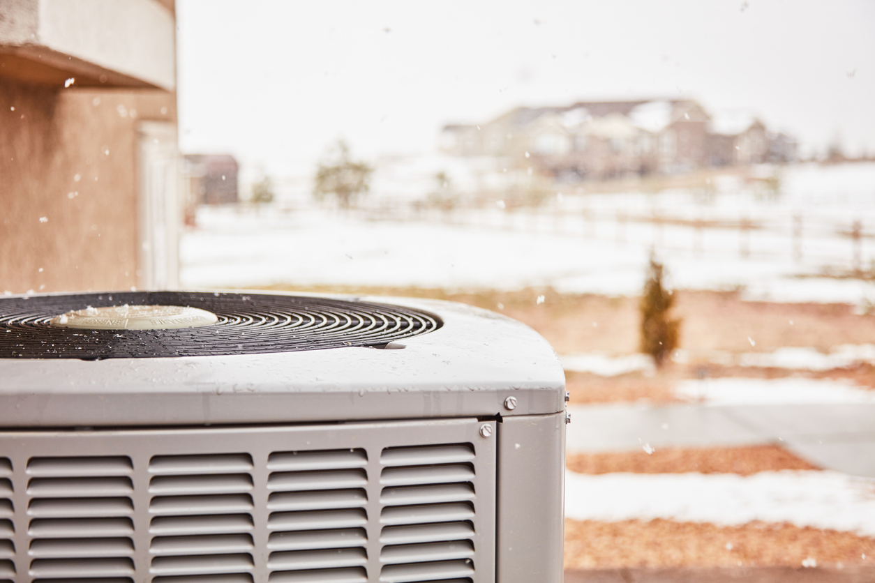 Residential air conditioning unit with snow falling in winter.